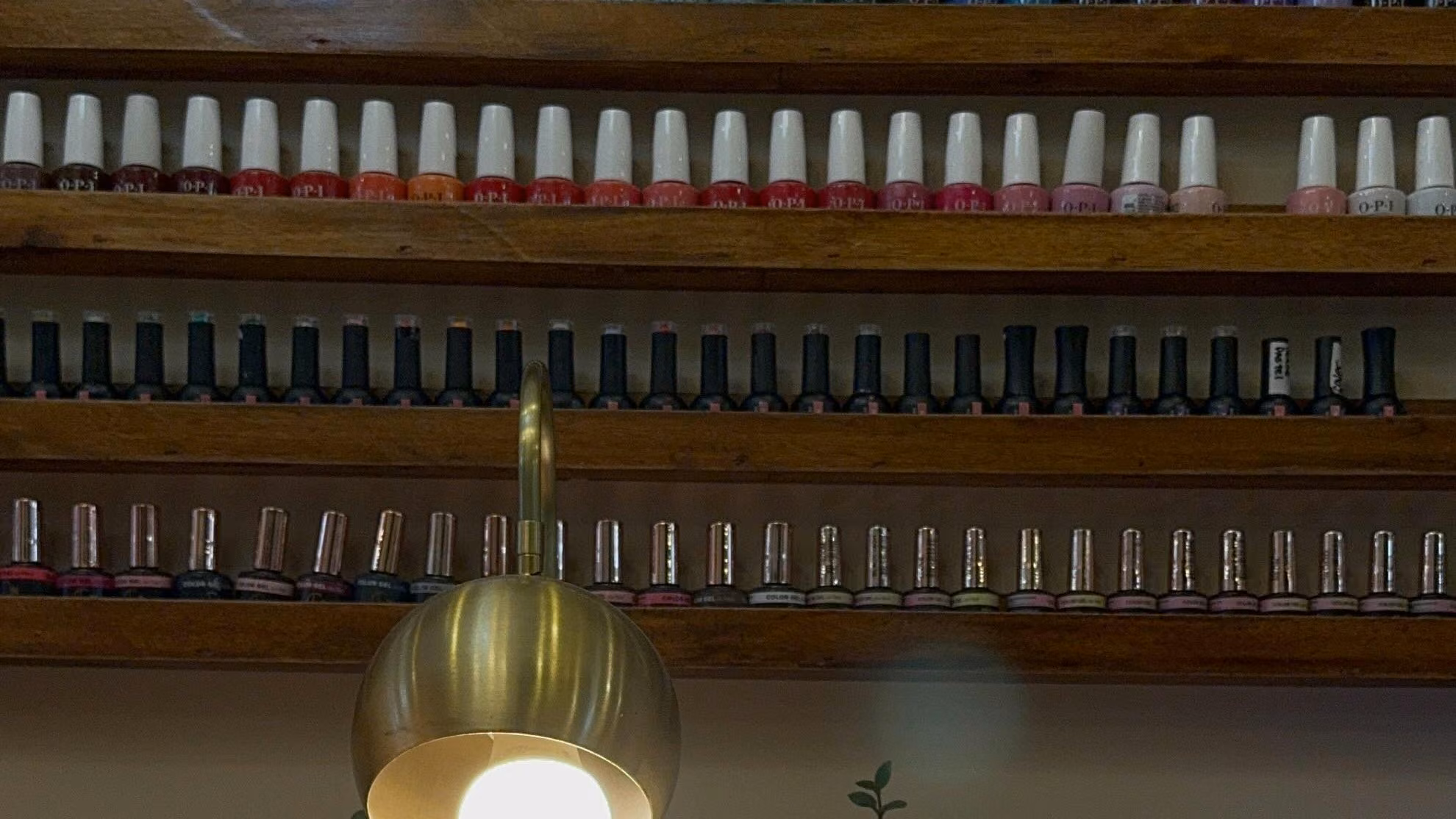 Pared de esmaltes y lámpara dorada en la mesa de manicuría